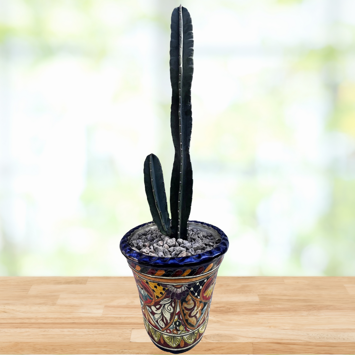 Tall Peruvian apple cactus, Cereus peruvianus in a decorative talavera pot on a wooden surface with a blurred green background